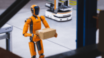 Humanoid robot carrying a box in a warehouse alongside an autonomous mobile robot